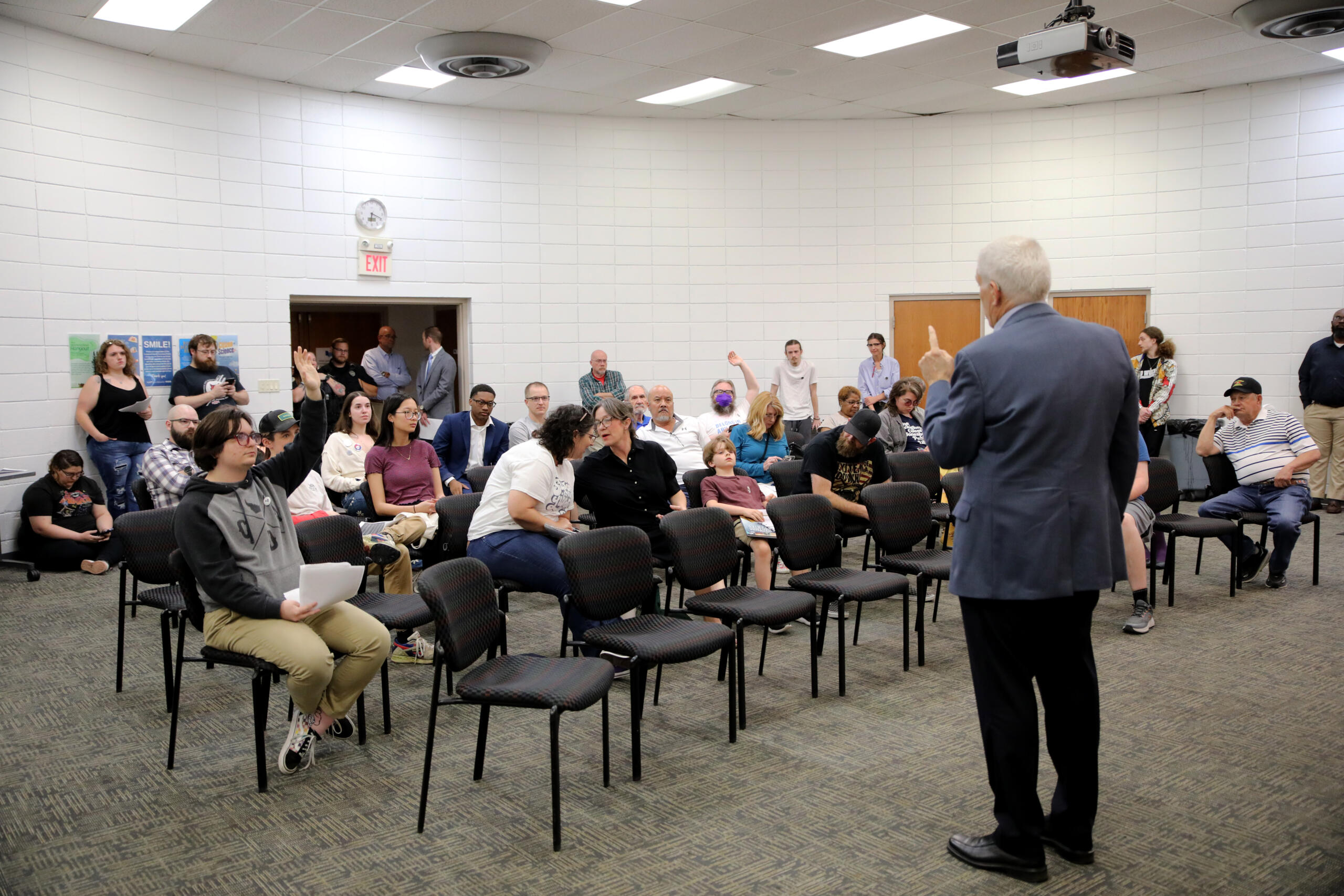 Attendees wait with hands raised to ask Sullivan questions.