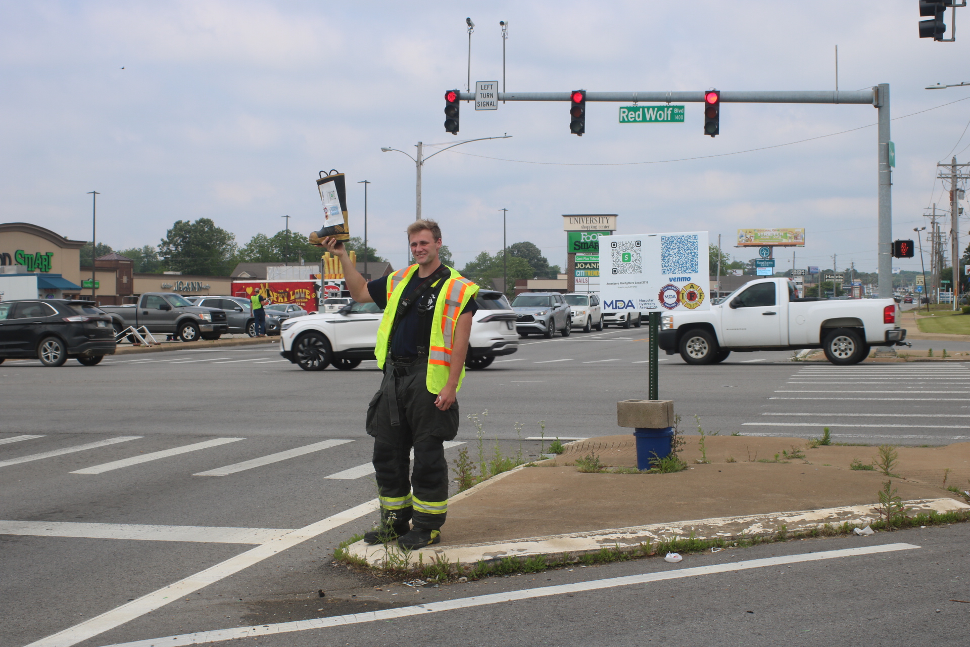 Jonesboro Fire Department Rookie Hunter Pagan poses with the boot on the intersection of Red Wolf Boulevard and Nettleton Avenue.