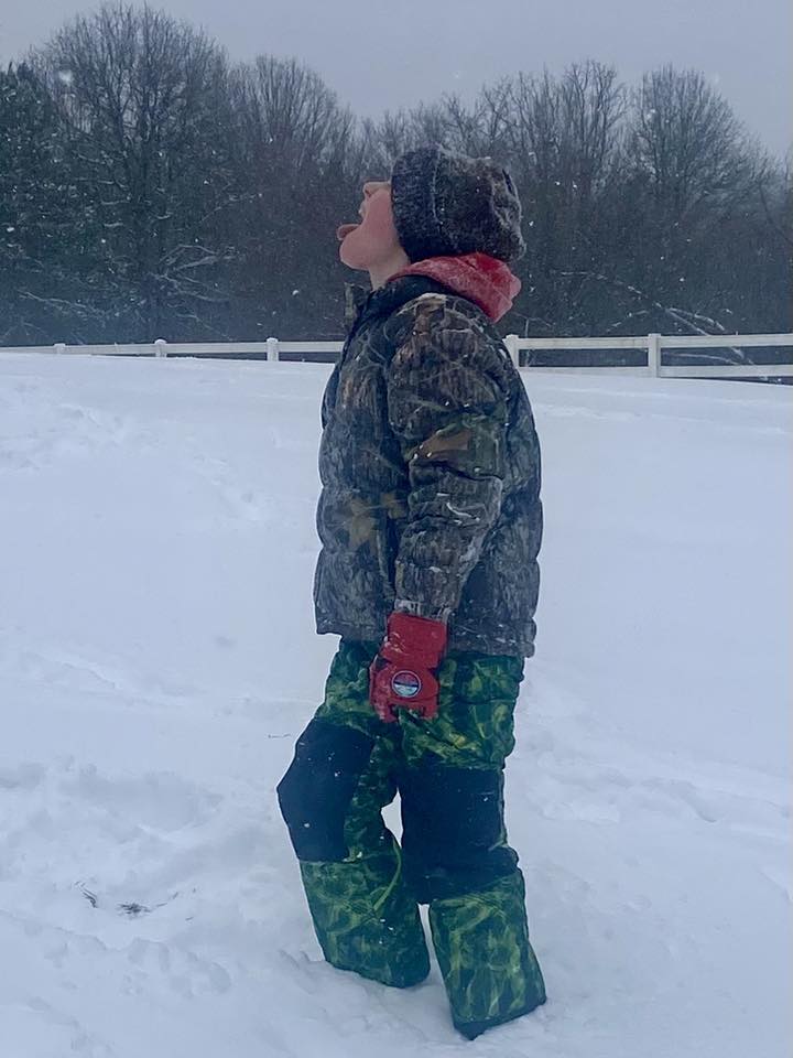 Boy in snow looking up at sky