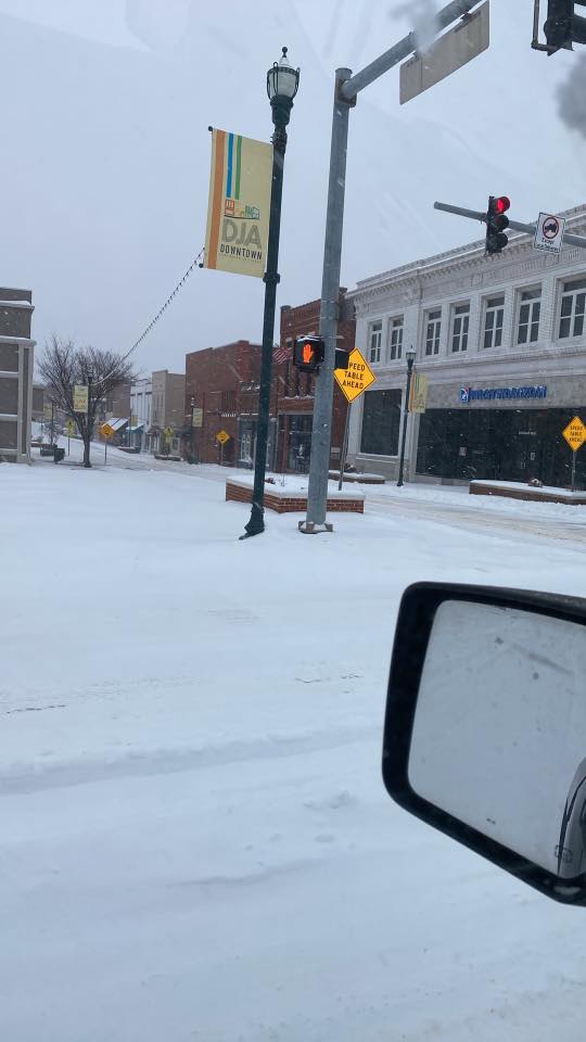 downtown jonesboro covered in snow as seen from a car