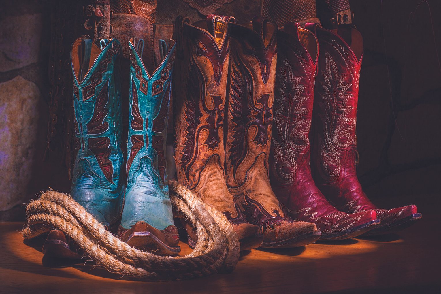 three cowboy boot sets in a row, blue tan and pink