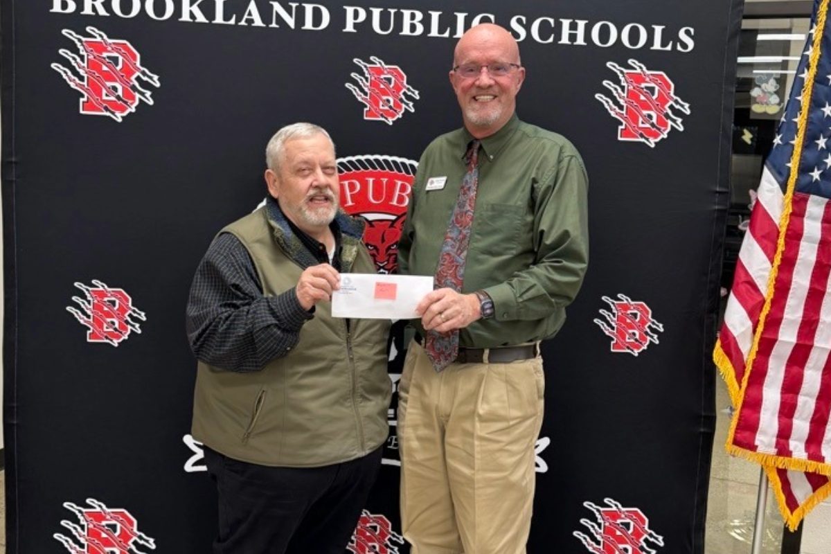 two men stand in front of step and repeat holding a check