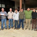 8 men ranging in age pose in a semi circle
