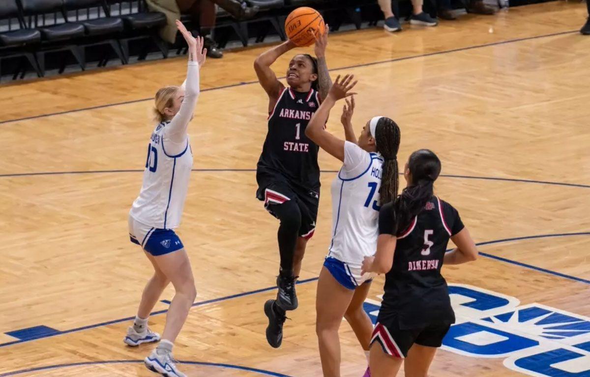 four basketball players two in black A-State jerseys two in white jerseys on court one player is shooting