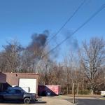 black smoke in front of buildings and parking lot