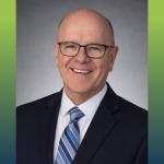 head shot of a man with blue suit and blue striped tie