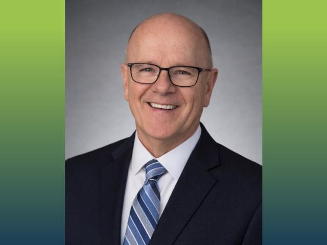 head shot of a man with blue suit and blue striped tie