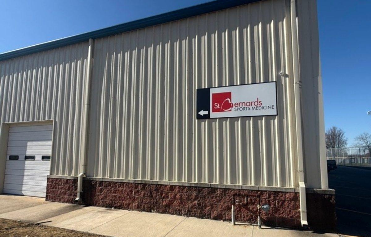 Tan building with brick base and sign that says St Bernards Sports Clinic