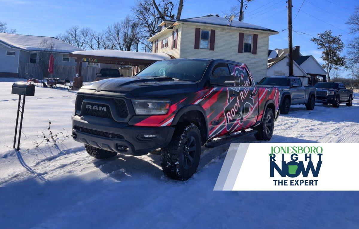 black truck with roof raiders logo sitting in front of house