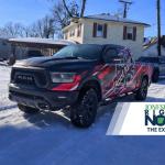 black truck with roof raiders logo sitting in front of house
