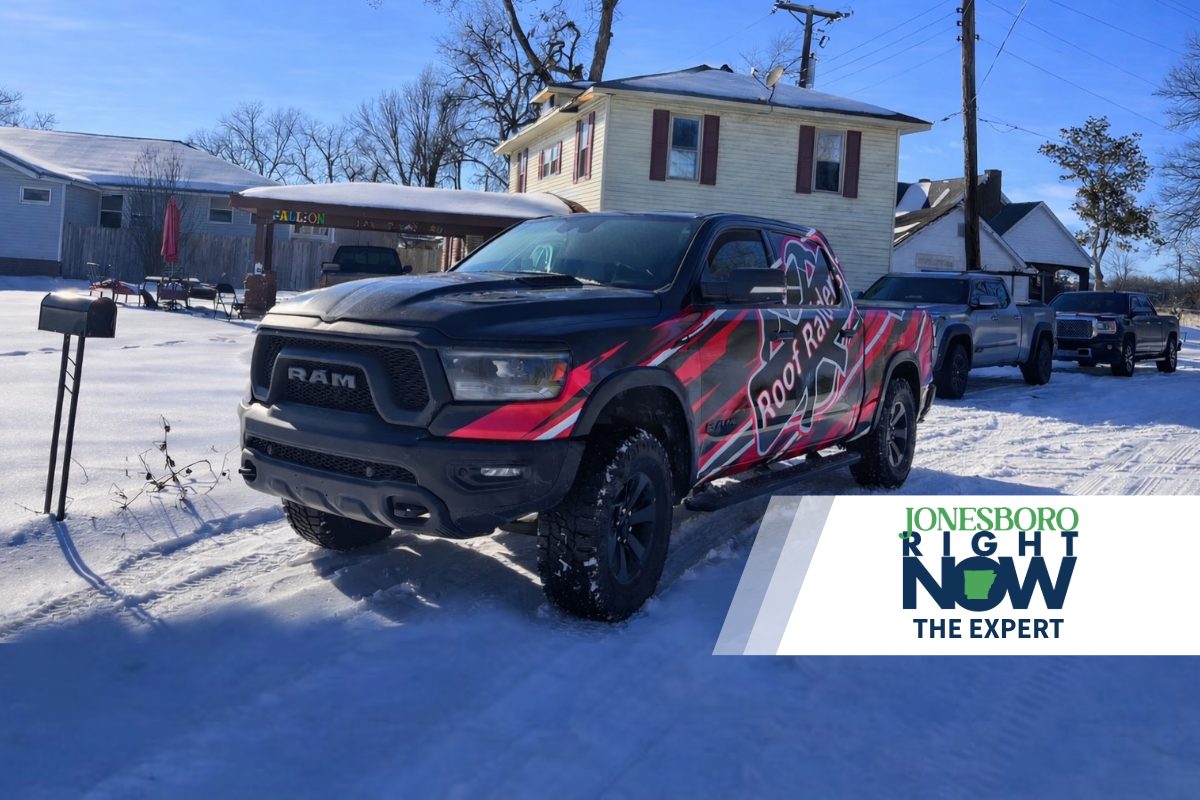 black truck with roof raiders logo sitting in front of house