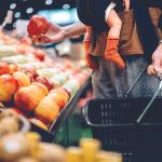 man holds basket and baby at grocery store