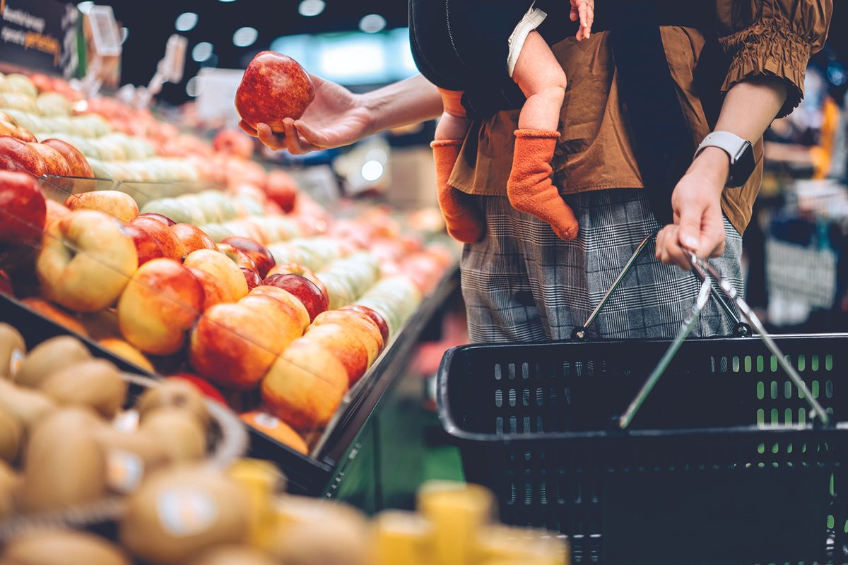man holds basket and baby at grocery store