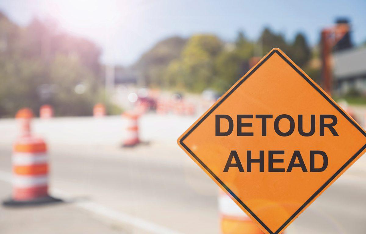 detour ahead sign in front of traffic barrels