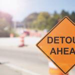 detour ahead sign in front of traffic barrels