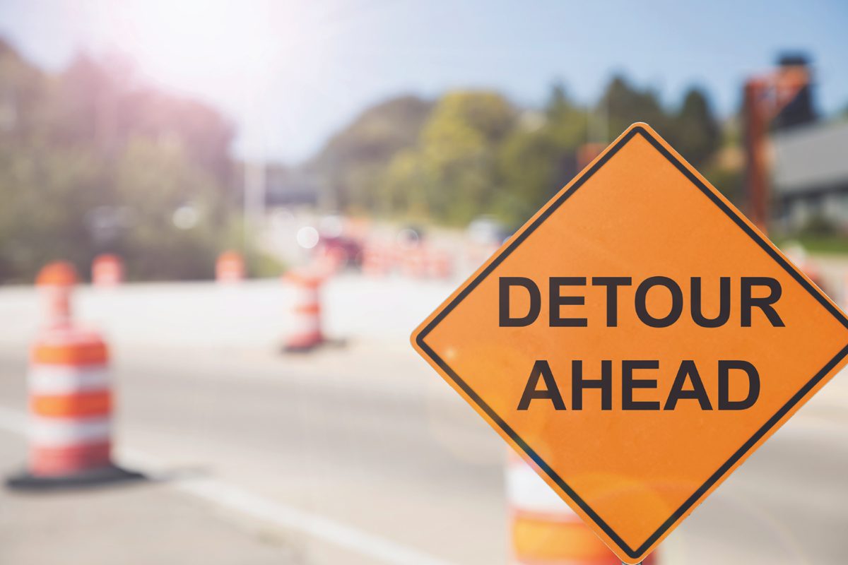 detour ahead sign in front of traffic barrels