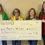four women hold check for $10,000