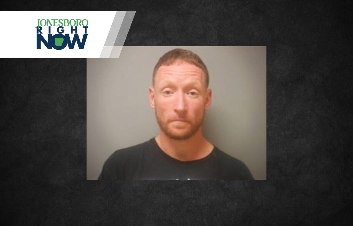 Mugshot photo of a man with short reddish hair and beard in a black shirt, against a gray background, with the Jonesboro Light Now logo in the top-left corner.