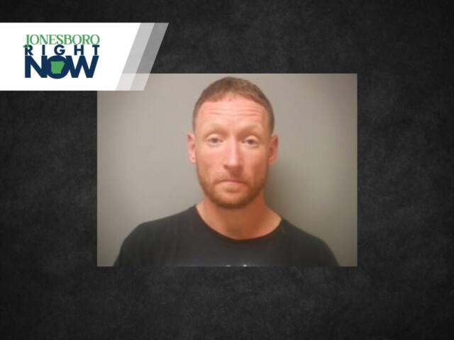 Mugshot photo of a man with short reddish hair and beard in a black shirt, against a gray background, with the Jonesboro Light Now logo in the top-left corner.