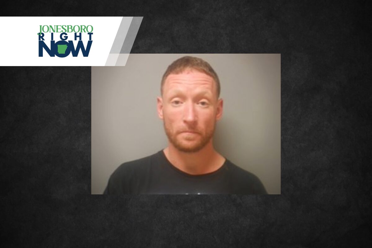 Mugshot photo of a man with short reddish hair and beard in a black shirt, against a gray background, with the Jonesboro Light Now logo in the top-left corner.