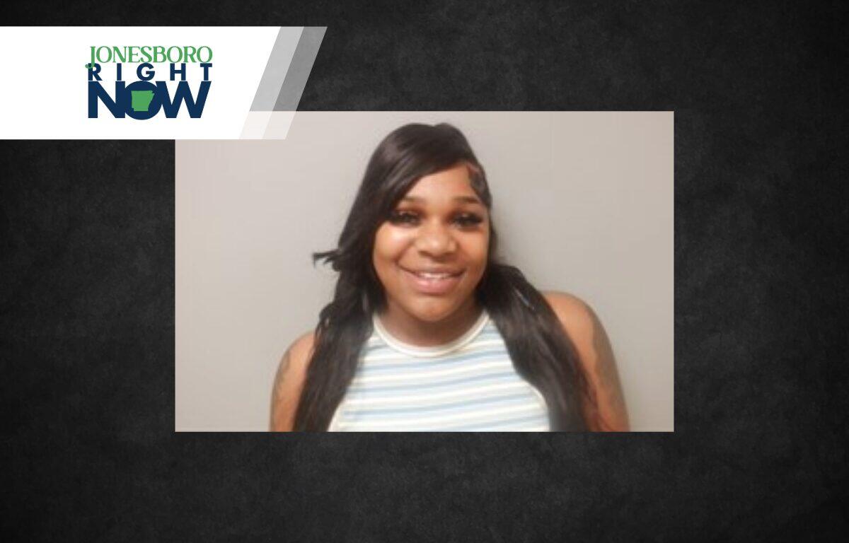 Smiling woman with long dark hair in a striped sleeveless top, head-and-shoulders portrait against a gray backdrop, with a Jonesboro Right Now banner in the corner.