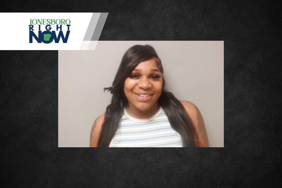 Smiling woman with long dark hair in a striped sleeveless top, head-and-shoulders portrait against a gray backdrop, with a Jonesboro Right Now banner in the corner.