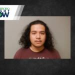Mugshot of a young man with shoulder-length curly hair in a maroon shirt, gray backdrop, with a Jonesboro Right Now banner at top-left.