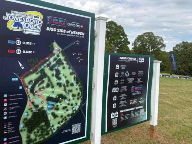 Signboard at a disc golf course showing the Jonesboro Open map and 'Disc Side of Heaven' championship course information.