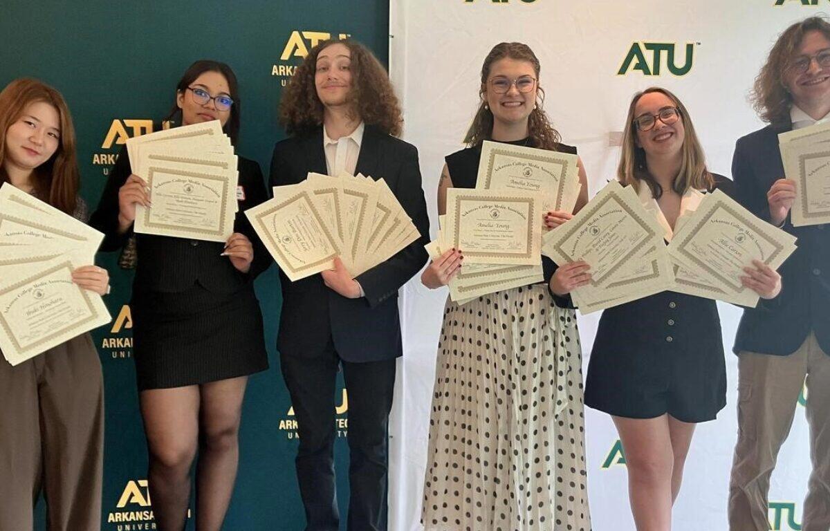 Six students in smart attire proudly display certificates at an ATU event with a branded backdrop behind them.