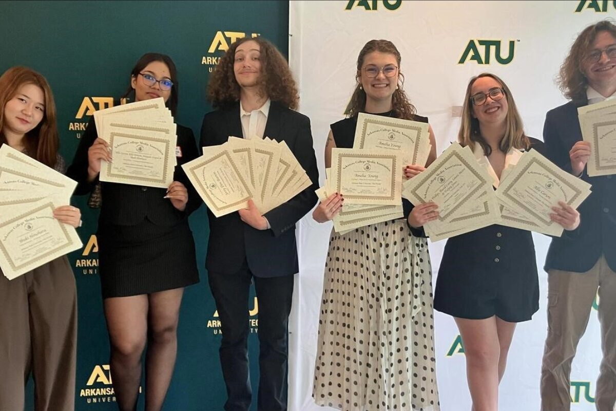 Six students in smart attire proudly display certificates at an ATU event with a branded backdrop behind them.
