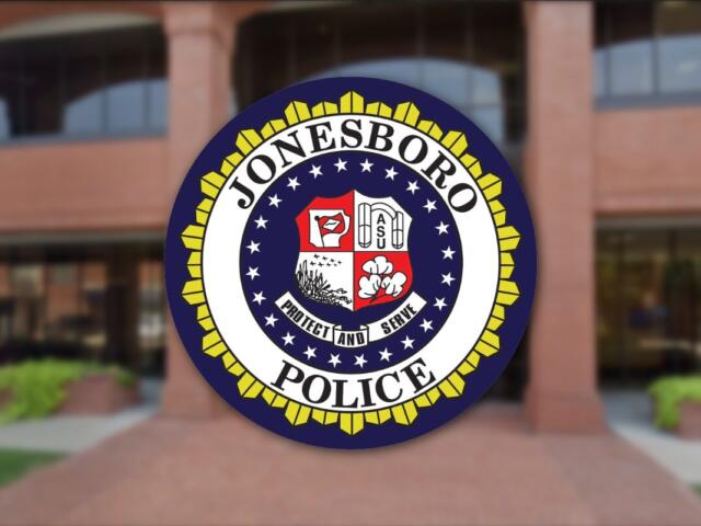 Circular Jonesboro Police Department seal with a yellow outer border, displayed on a brick building entrance in the background.