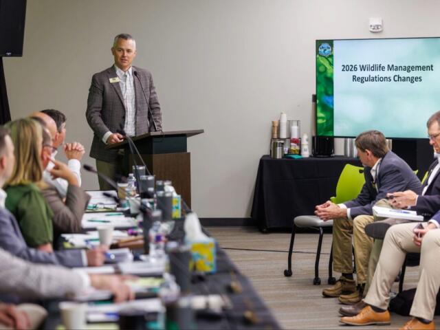 man in gray suit presents before room of people