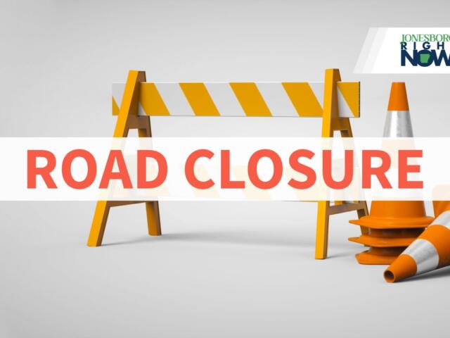 Road closure sign: orange barricade with traffic cones and a bold 'ROAD CLOSURE' text overlay; logo in the top-right corner.