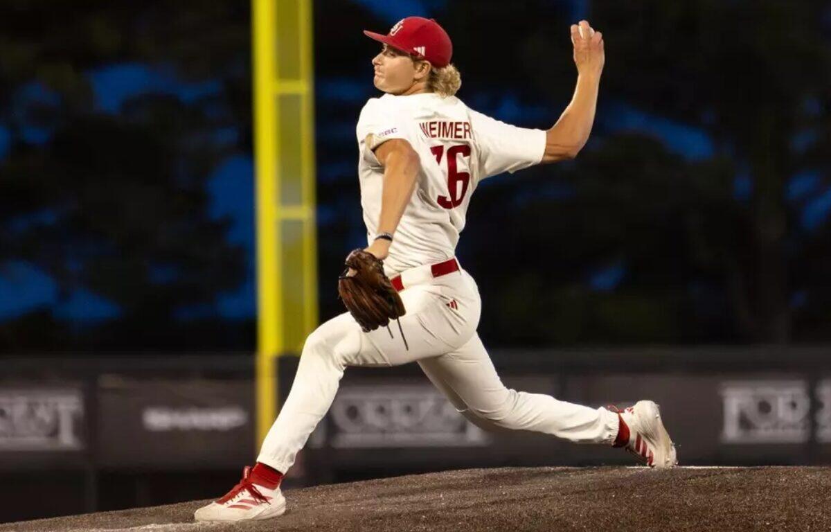 Baseball pitcher in a white uniform throwing a pitch from the mound during a game.