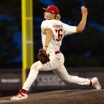 Baseball pitcher in a white uniform throwing a pitch from the mound during a game.