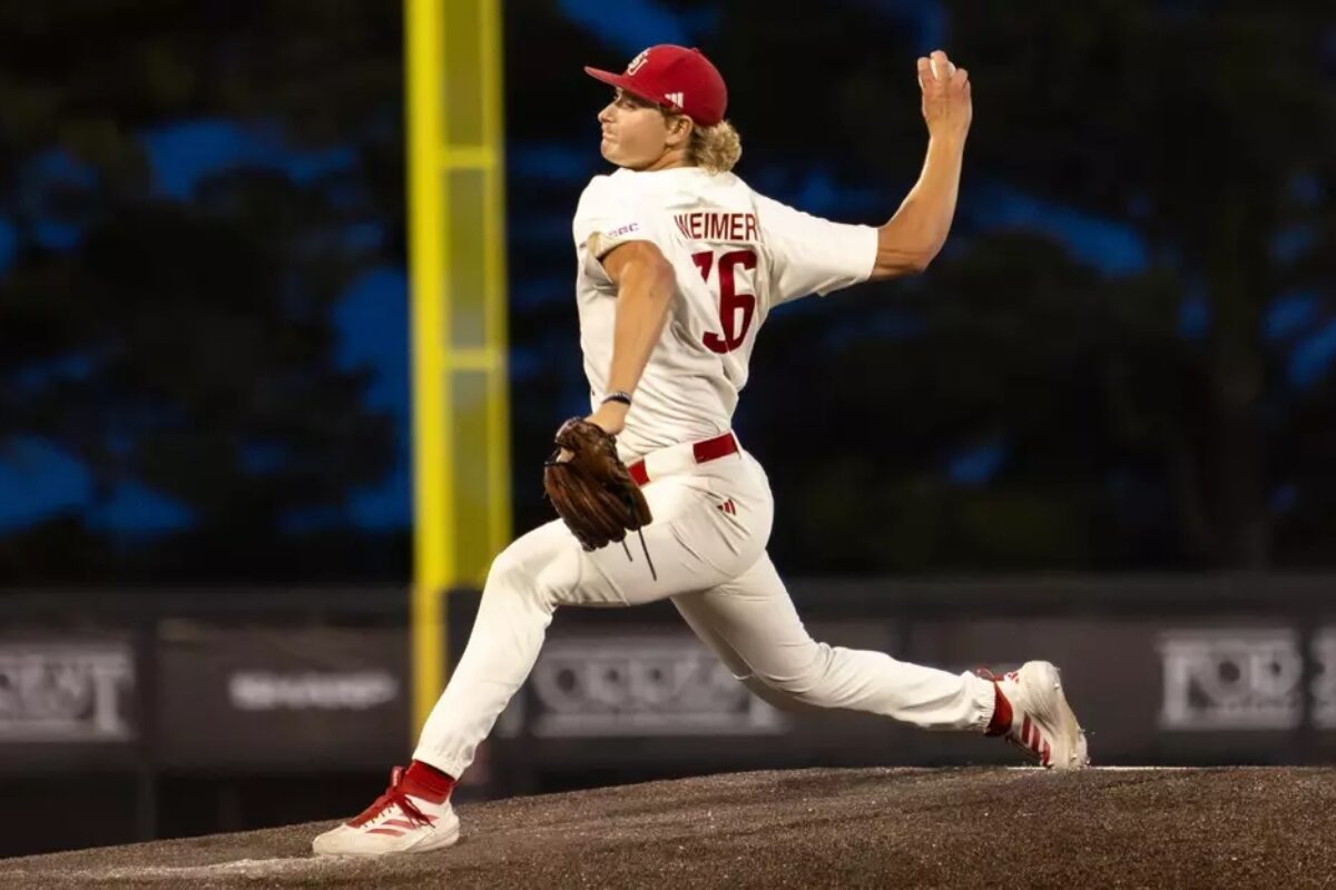 Baseball pitcher in a white uniform throwing a pitch from the mound during a game.