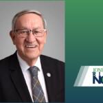 Smiling older man in a dark suit, white shirt, and patterned tie, wearing glasses, against a gray backdrop with a 'Jonesboro Right Now' logo on the right.