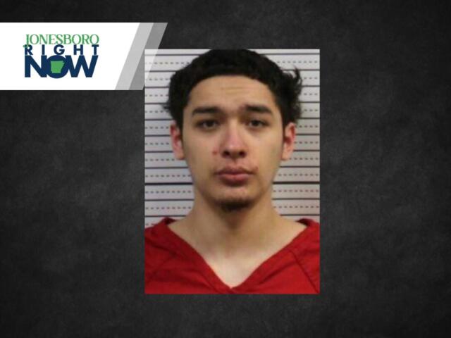 Mugshot of a young man with dark hair wearing a red shirt, posed against a measurement background; Jonesboro Right Now logo in the top-left corner.