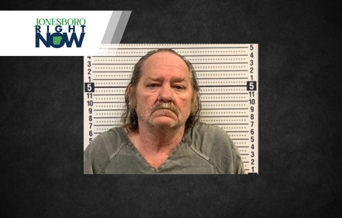 Mugshot of a middle-aged man with long gray hair in front of a height-chart backdrop, with a Jonesboro Right Now logo overlayed in the top-left.