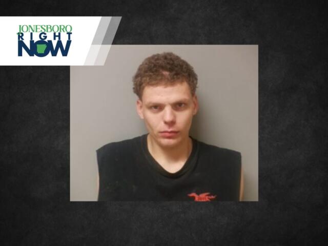 Mugshot of a young man with short curly hair in a black sleeveless shirt against a gray wall, with a Jonesboro Right Now logo in the top-left corner.