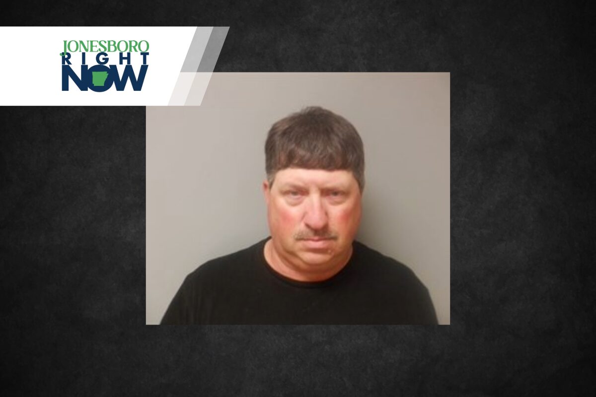 Mugshot-style photo of a middle-aged man in a black shirt, neutral gray backdrop, with a Jonesboro Right Now news banner in the top-left corner