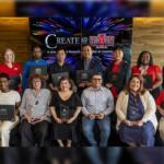 Group of diverse people posing with awards/plaques at a ceremony, banner reads 'Create @ State' in the background.
