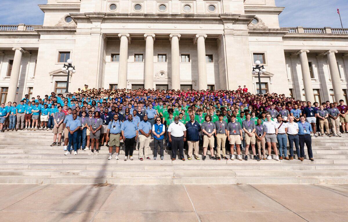 Large diverse group posing on the steps of a grand neoclassical building with tall columns.