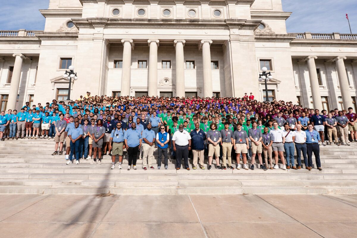 Large diverse group posing on the steps of a grand neoclassical building with tall columns.