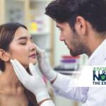 Medical professional wearing gloves examines a woman's face in a clinical setting.