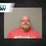 Mugshot-style portrait of a bald man with glasses and gray beard wearing a pink T‑shirt against a gray background; Jonesboro Right Now banner in the corner.