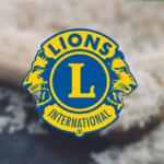 Lions Clubs International emblem in blue and gold centered on a blurred background.