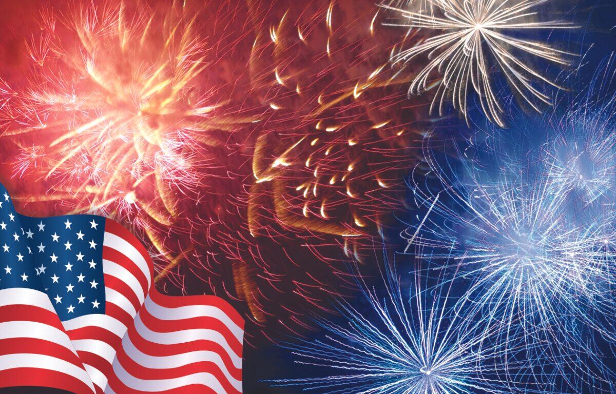 American flag waves in the foreground with red, white, and blue fireworks bursting in the night sky.