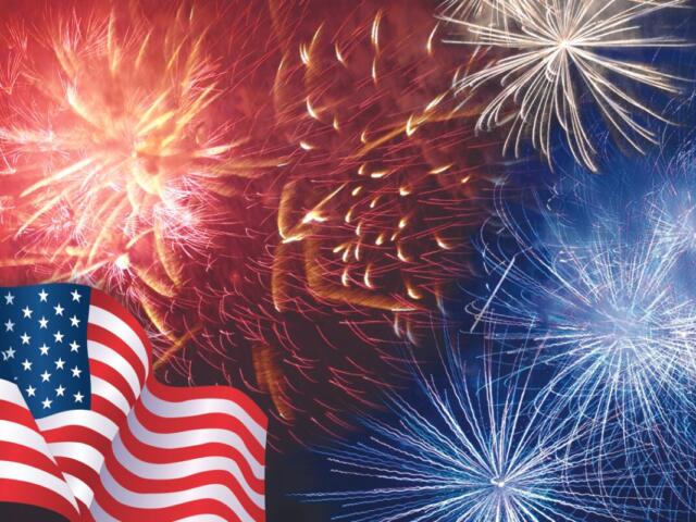 American flag waves in the foreground with red, white, and blue fireworks bursting in the night sky.