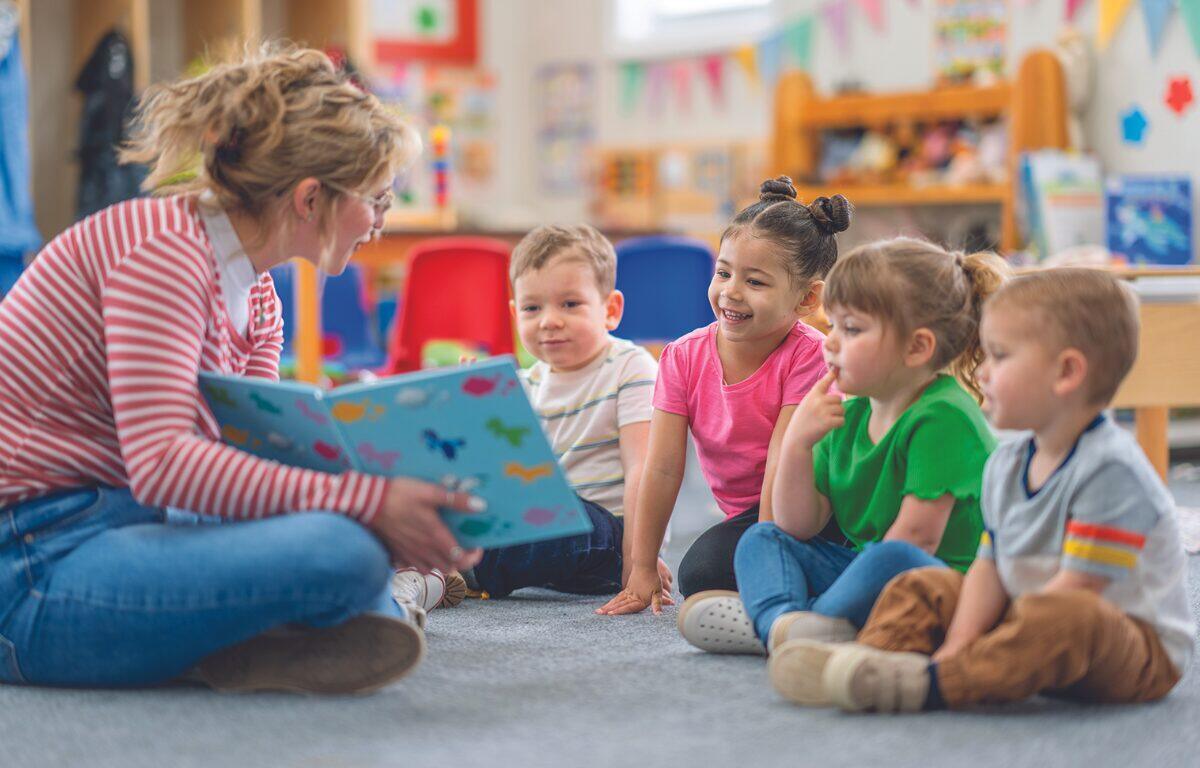 woman holding book and showing it to a group of young children